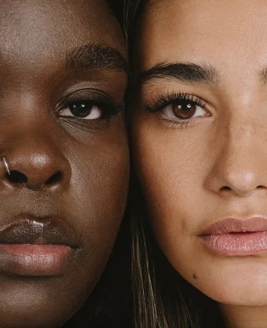 Two women pressed cheek to cheek, each wearing lash extensions