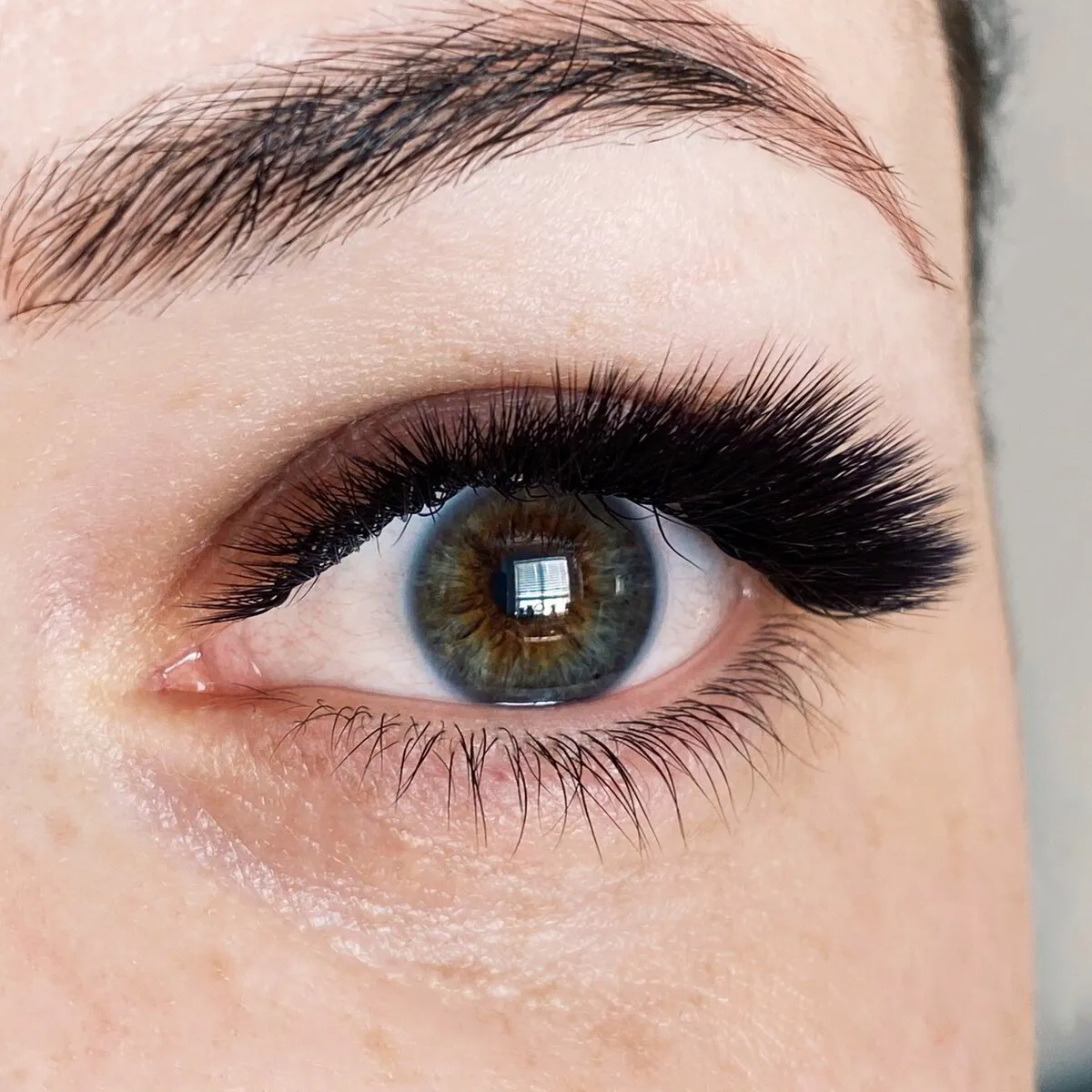 Dark, feathered mega volume lashes on a brown-green eye
