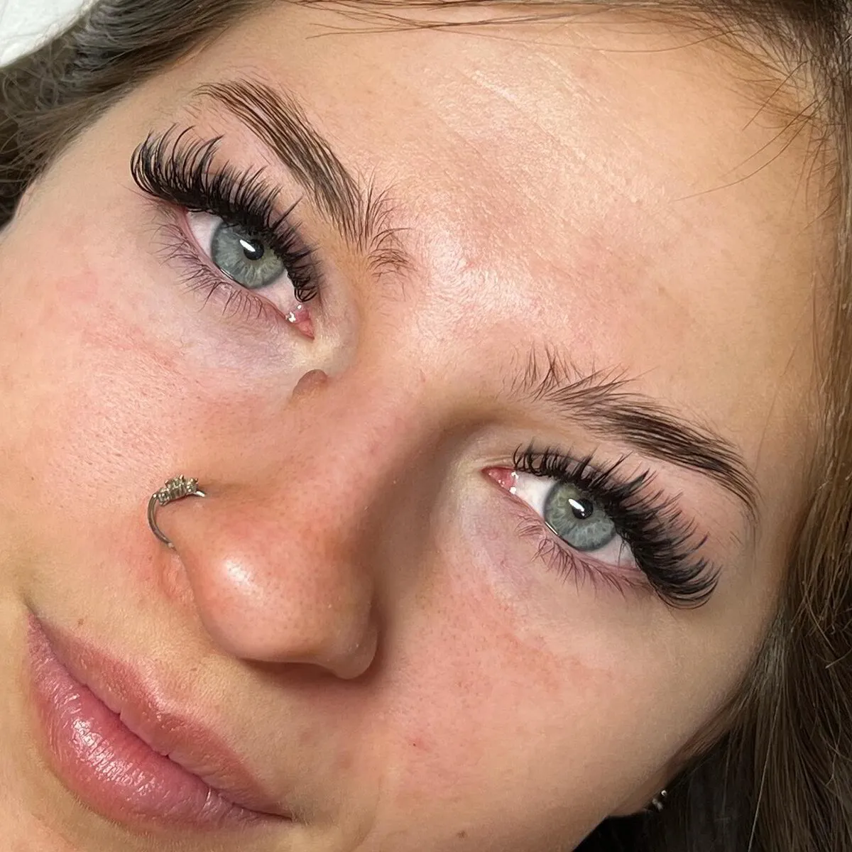 Wispy, spiky textured lash extensions on a client with green eyes