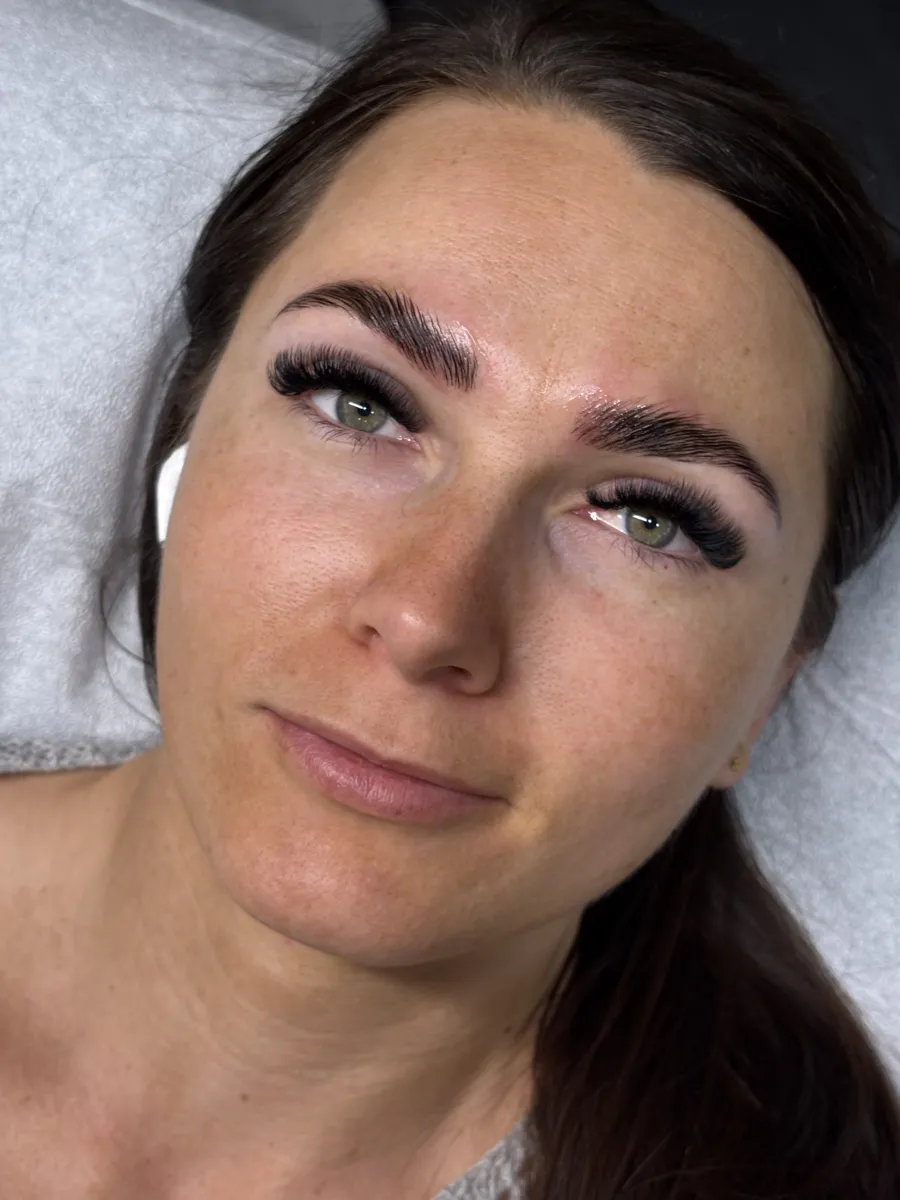 Freshly laminated and tinted brows above lash extensions on a woman with green eyes